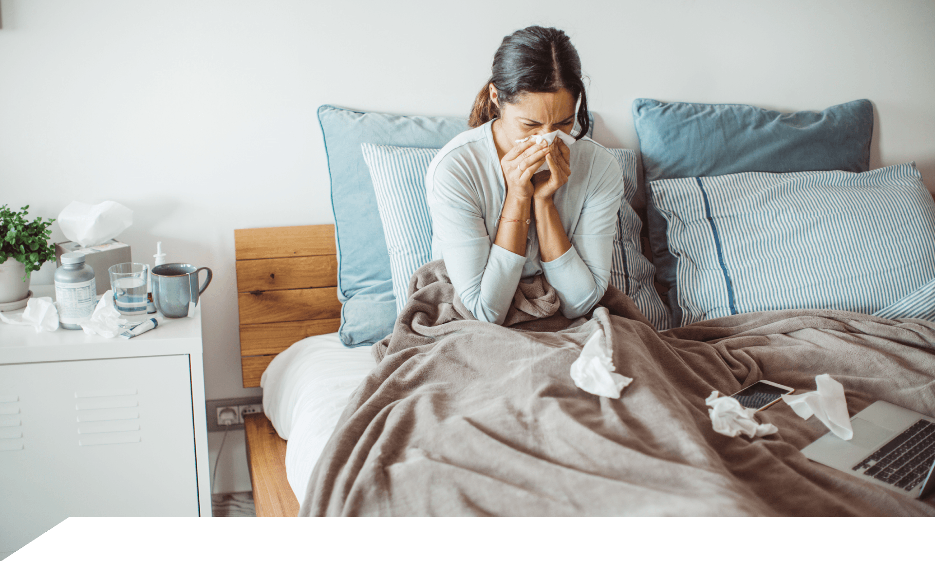 A woman in bed blowing her nose