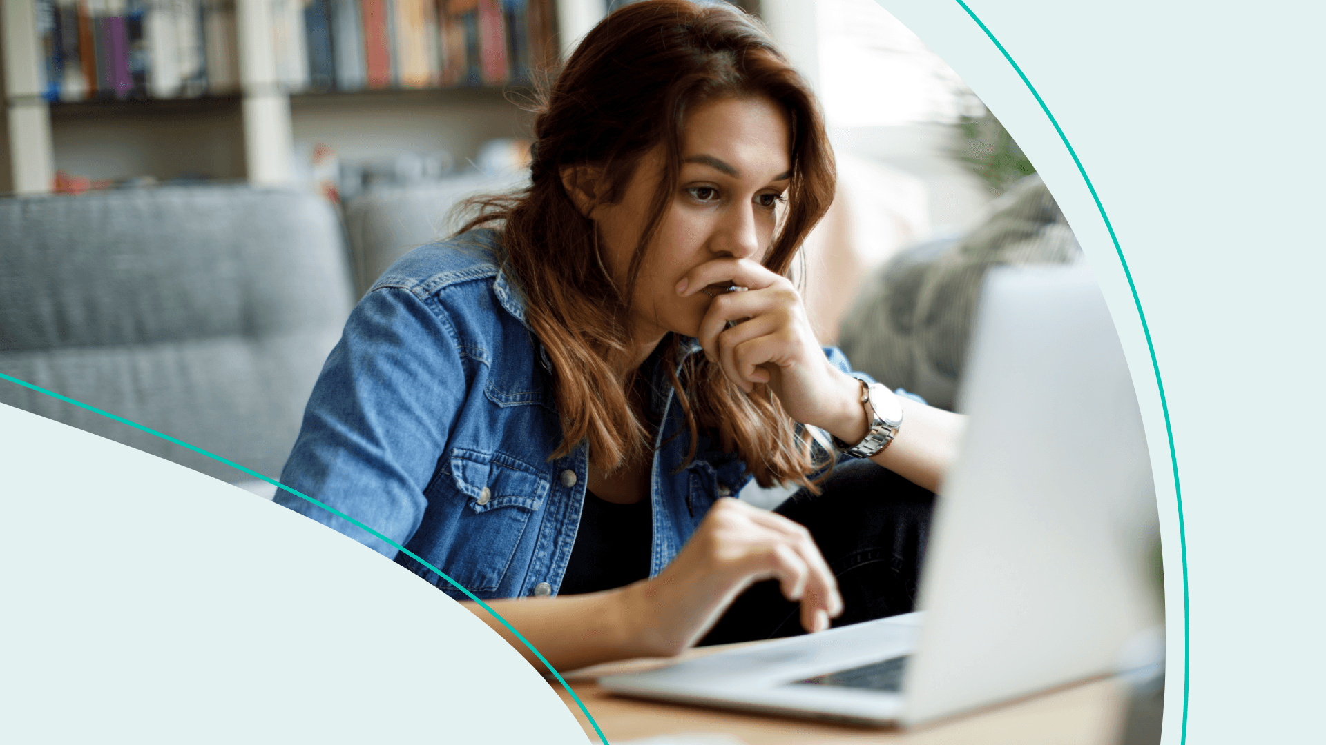 Woman sitting and looking at her laptop with her mouth over her face