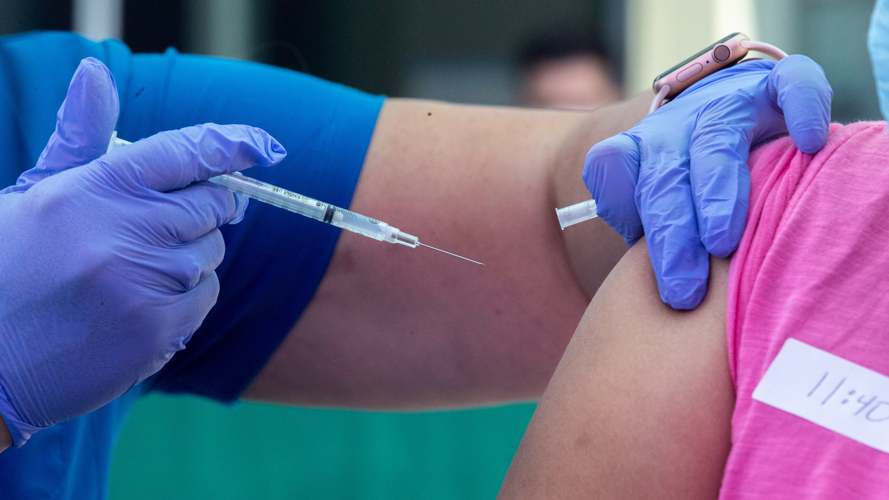 RN Amy Berecz-Ortega, left, inoculates a woman at a COVID-19 vaccine event
