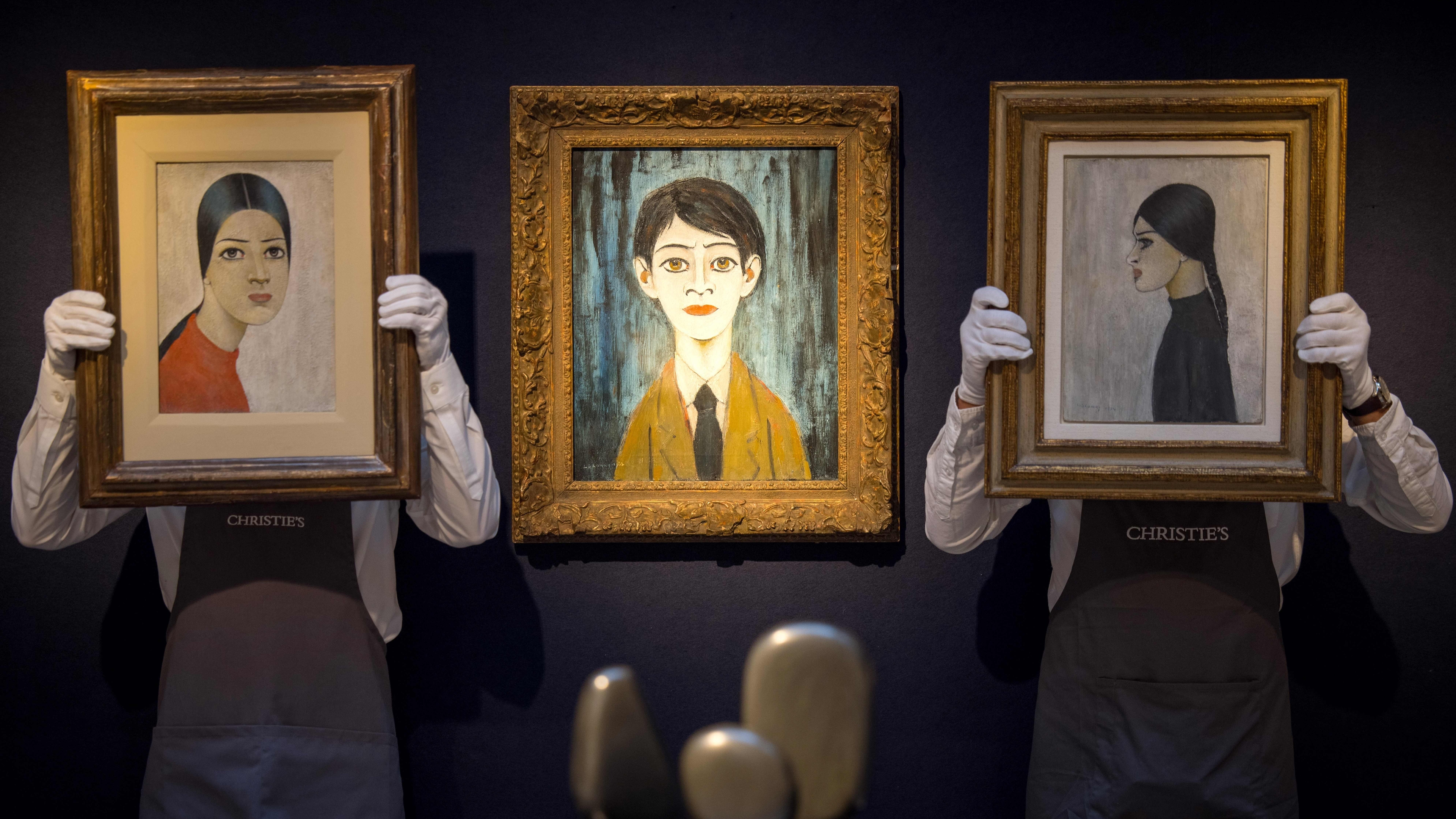 Gallery workers pose with artworks.