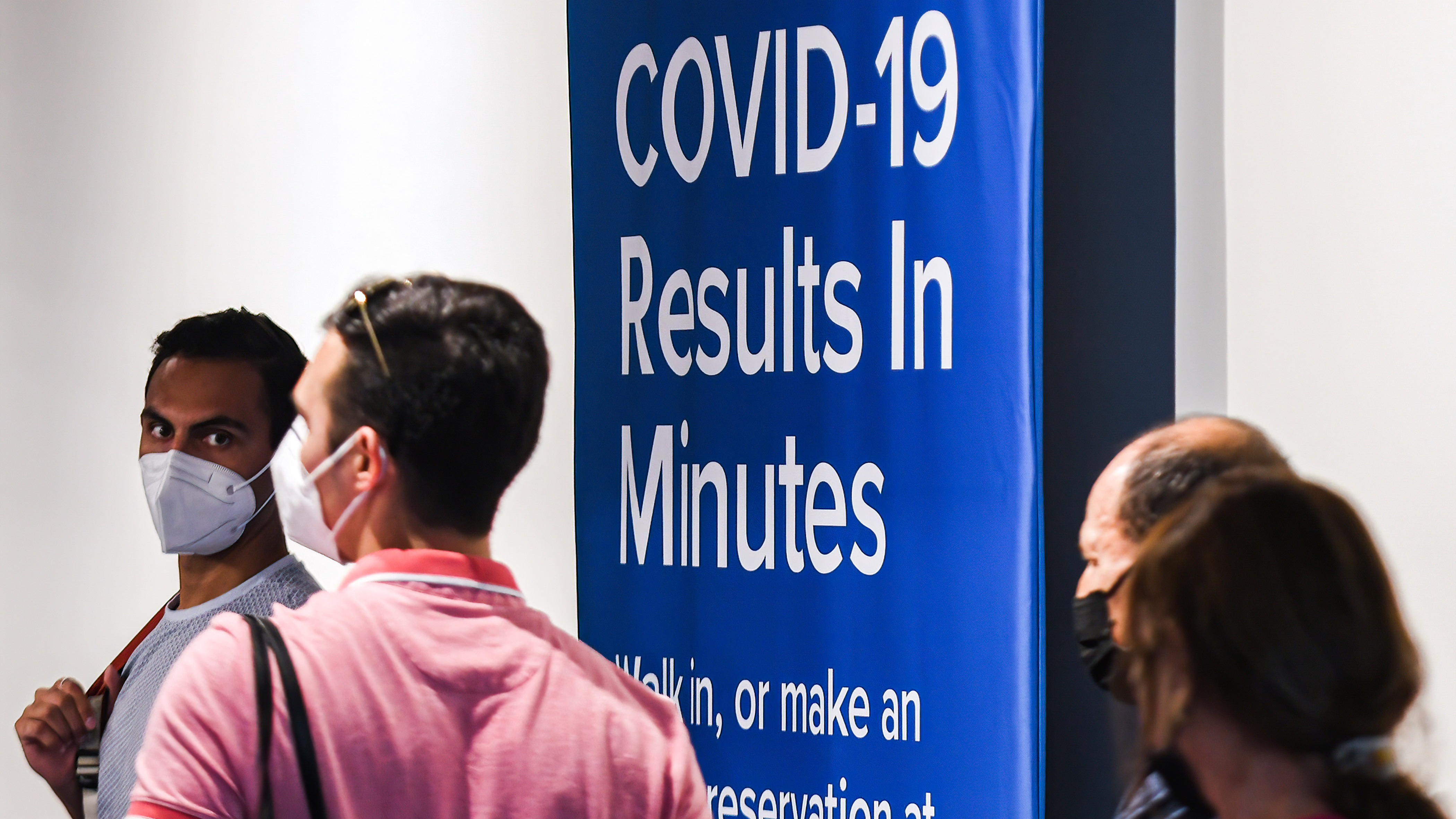 People wearing facemasks enter a COVID-19 testing site at Orlando International Airport.