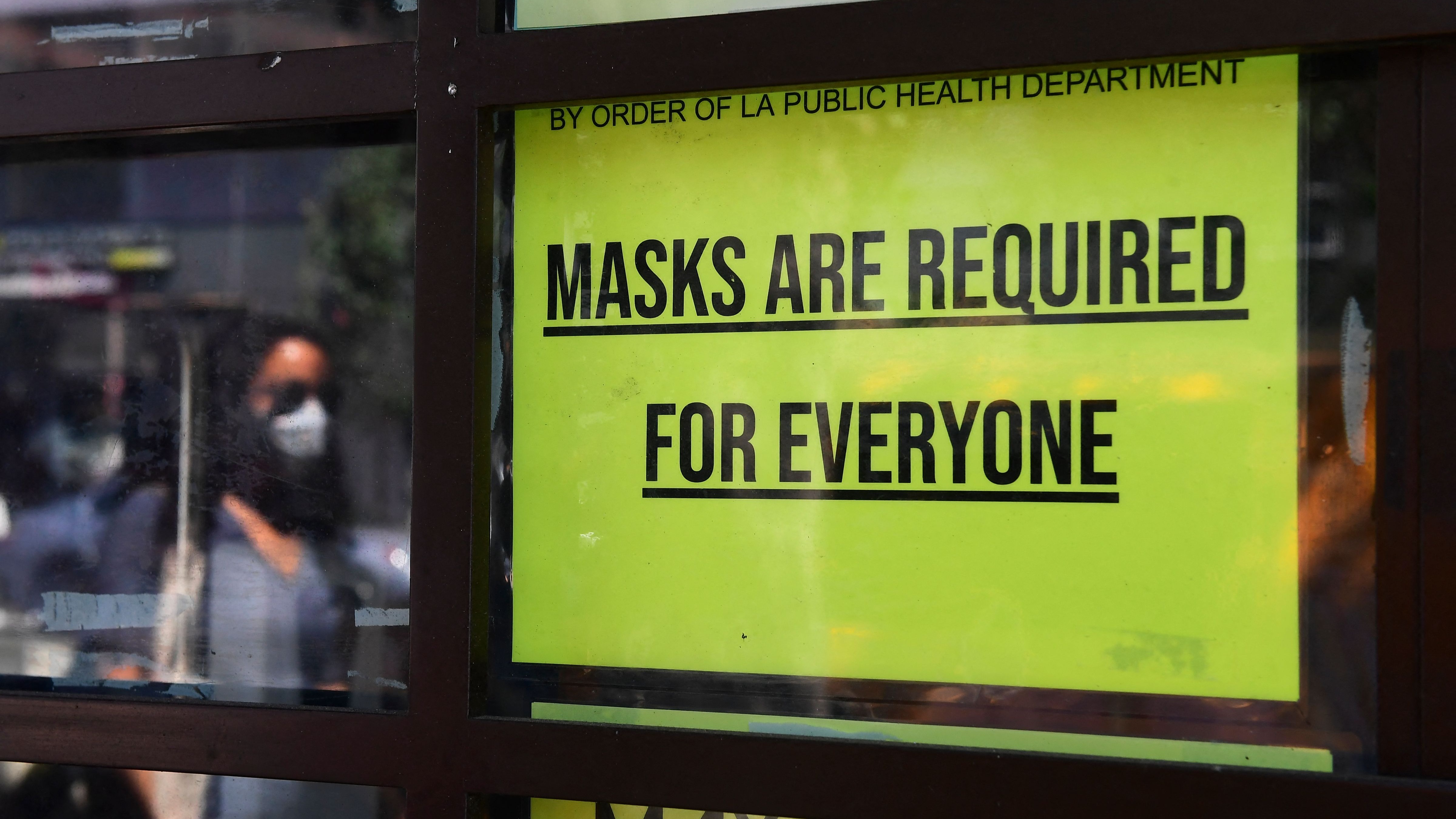 A storefront sign reminds people masks are for everyone
