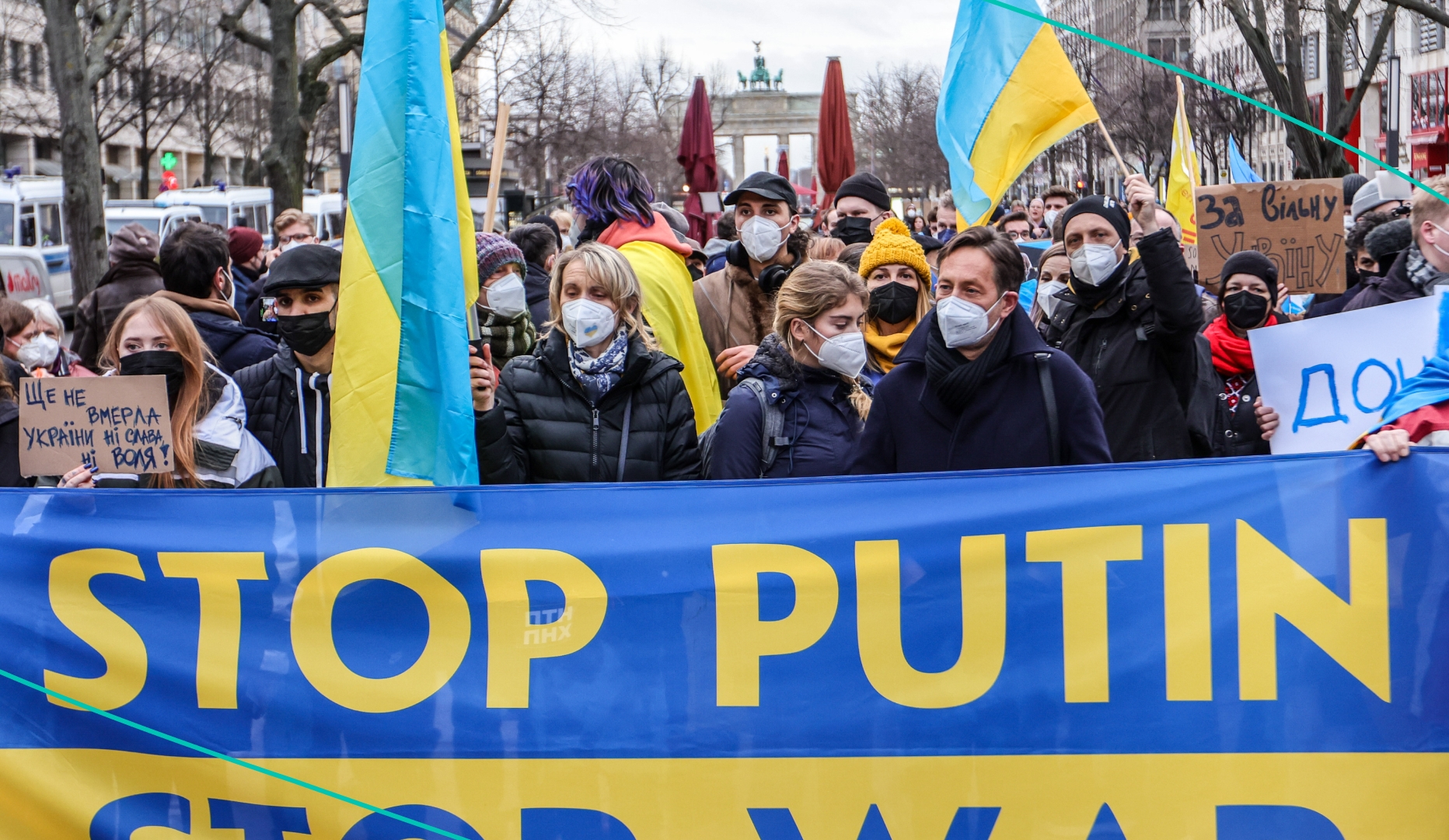 A woman holds a Ukrainian flag next to a banner reading stop Putin as youth groups protest Ukraine intervention