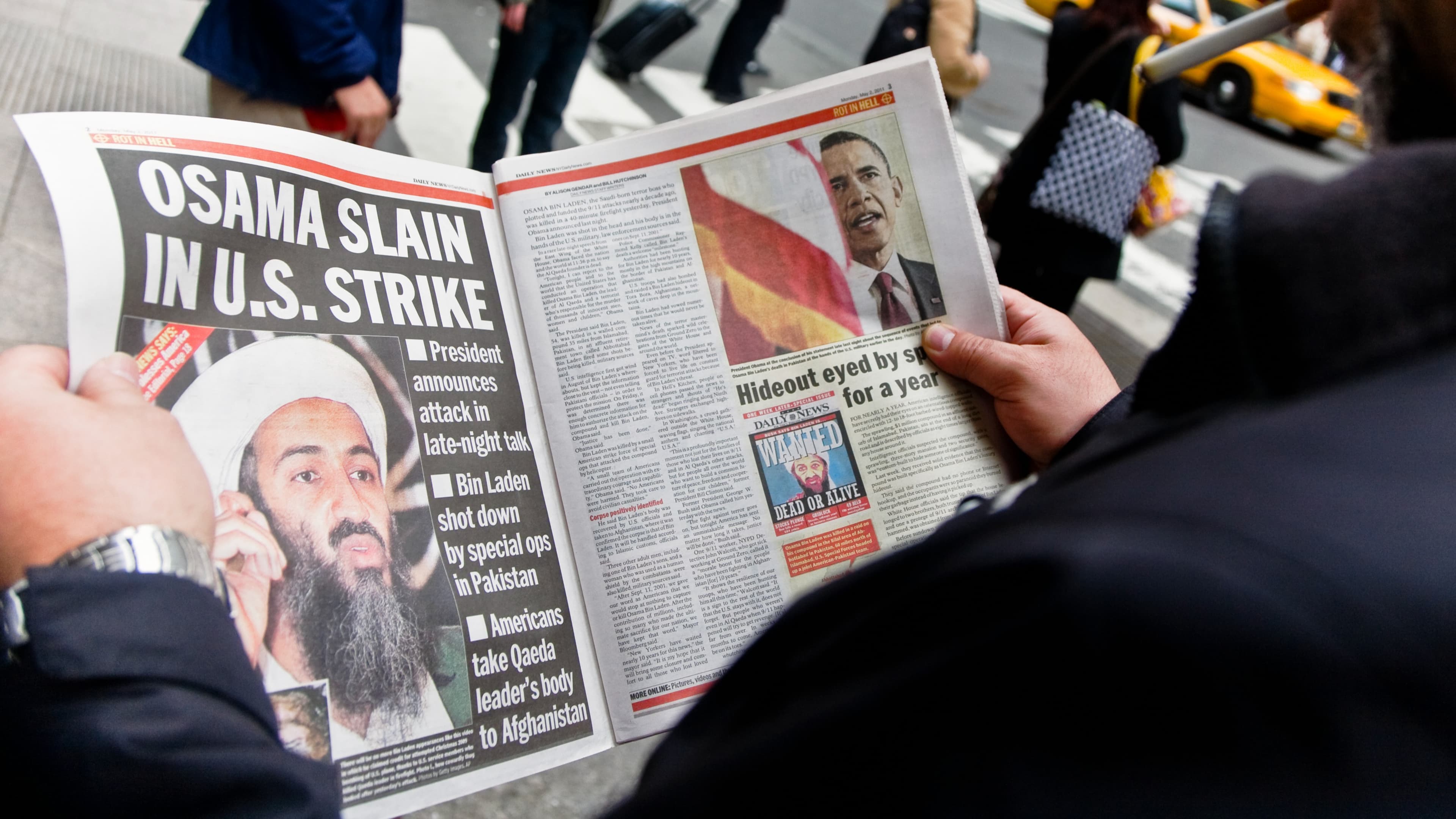A man reading the newspaper about Osama bin Laden's capture and death. Got Him and Rot in Hell are some of the headlines.