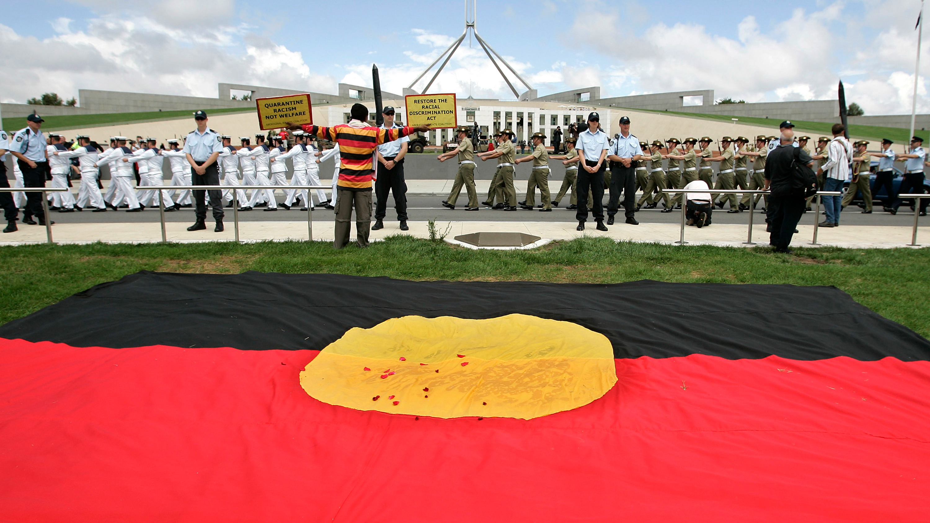 An Aborigonal protester sits outside Parliament House during the opening of the 42nd Parliament