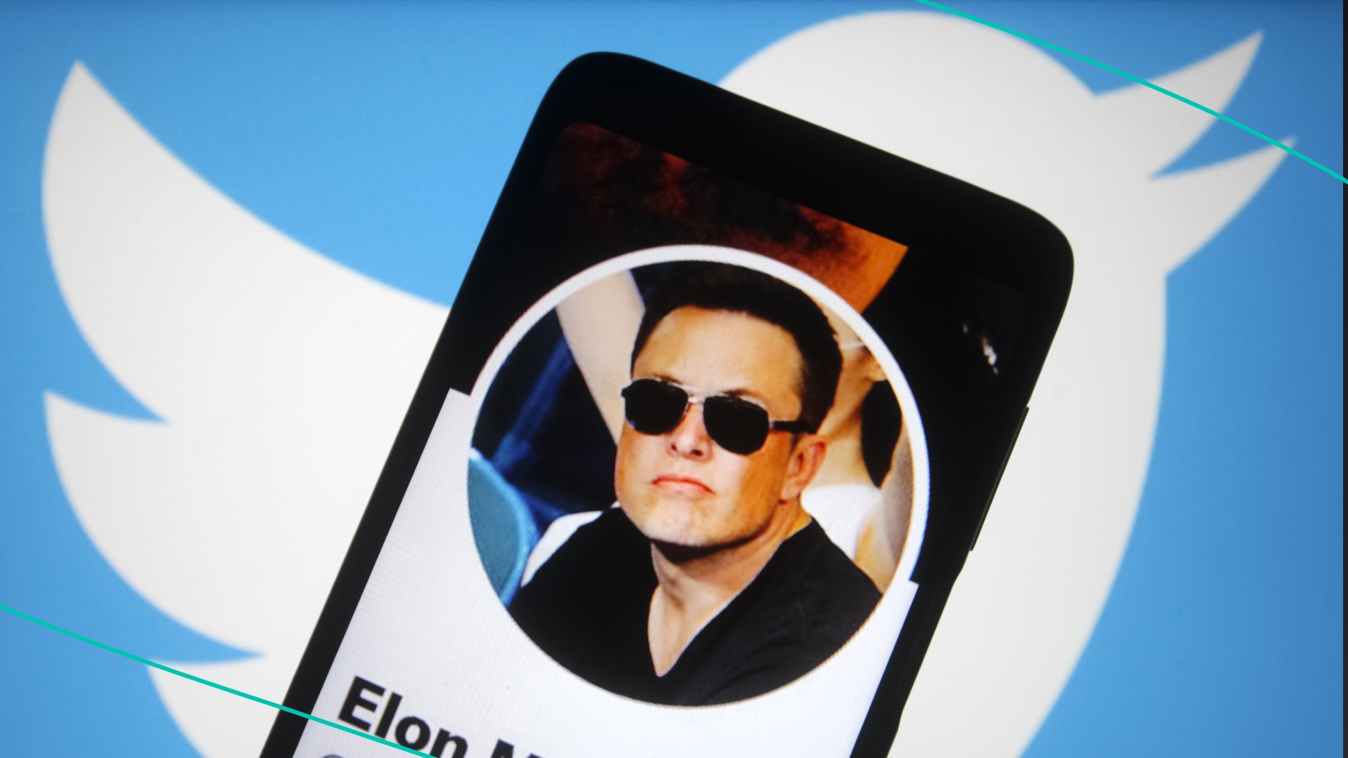 In this photo illustration, Twitter account of Elon Musk is seen on a smartphone screen and Twitter logo in the background.