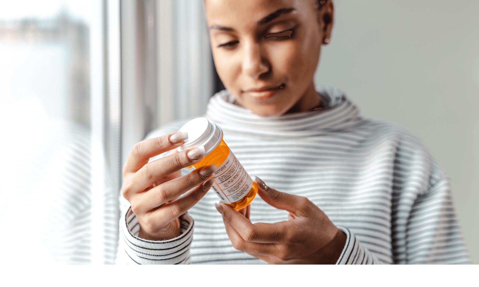 A woman looking at a bottle of pills