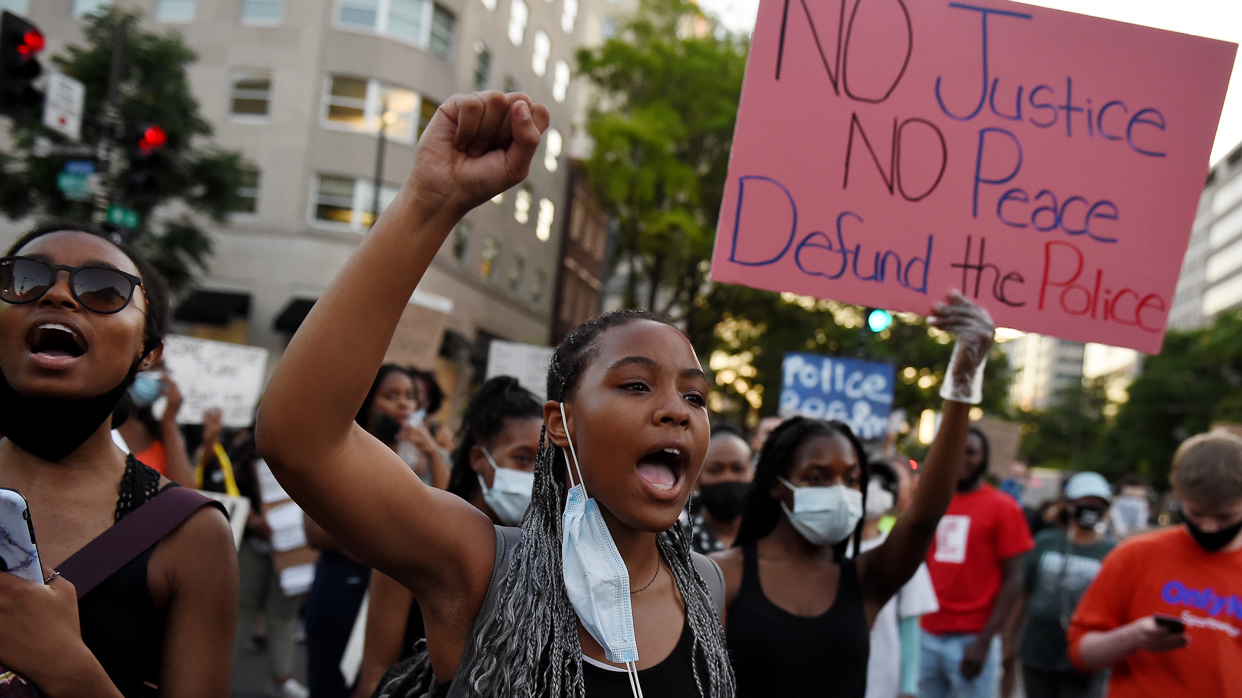 Demonstrators hold up placards and chant as they protest against police brutality and the death of George Floyd, across from the White House.