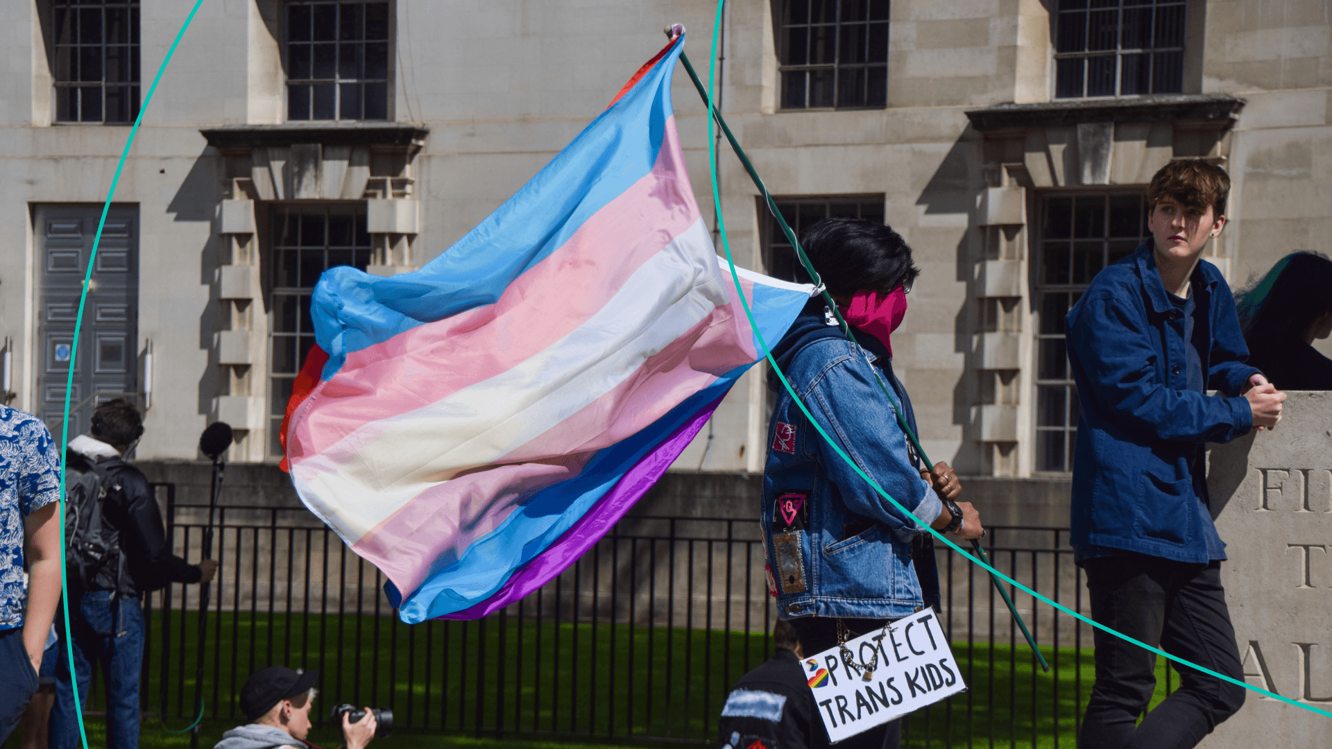 A protester holds a Trans Pride flag and a 'Protect Trans Kids' placard during the trans rights demonstration