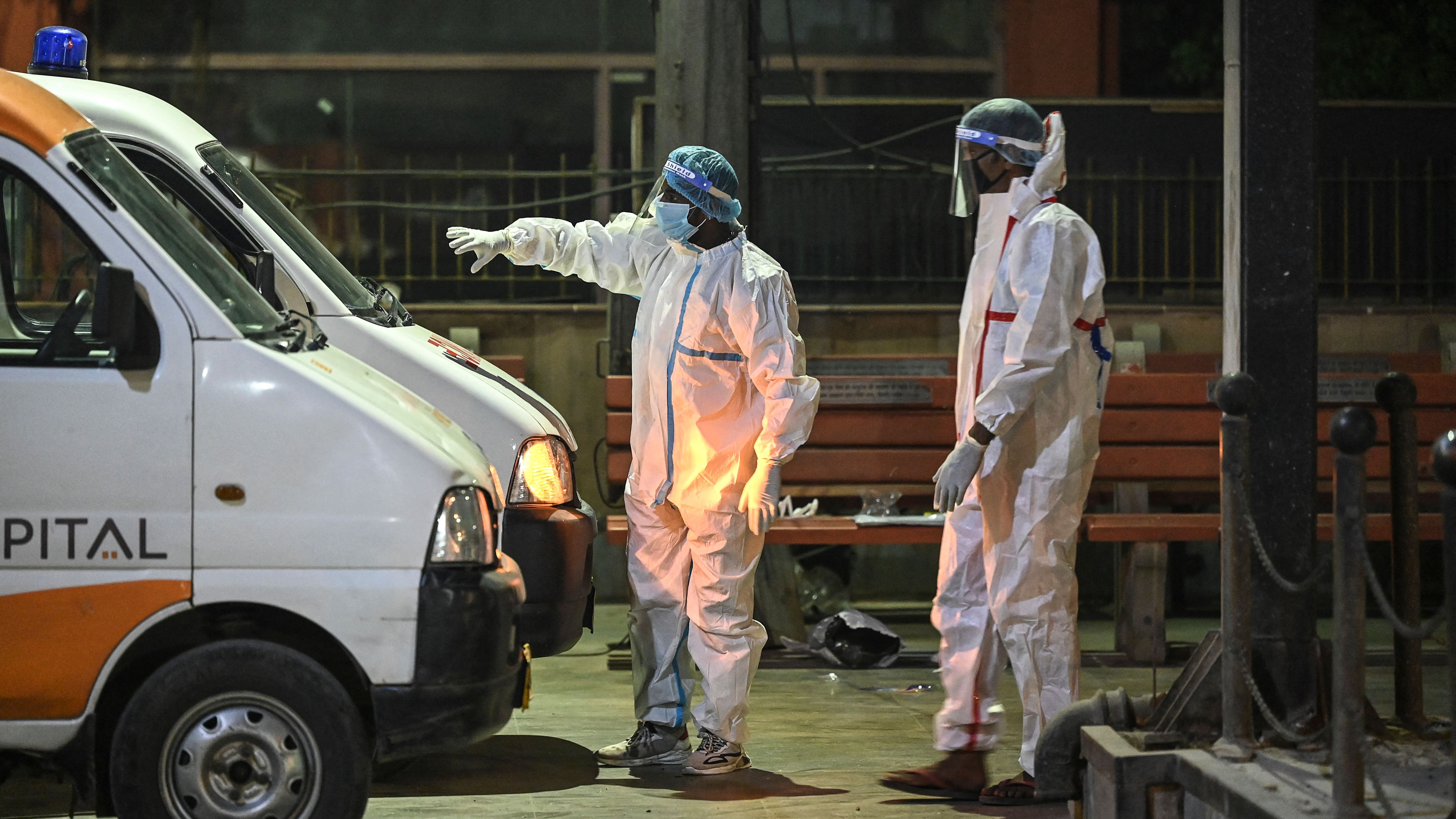 Crematorium staff members stand near ambulances carrying the bodies of Covid-19 victims for a cremation at Nigambodh Ghat Crematorium, on the banks of the Yamuna river in New Delhi in the early hour of April 22, 2021.