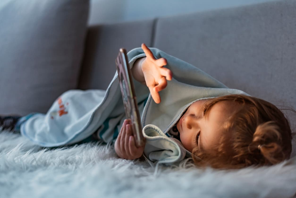 child laying on couch using a tablet