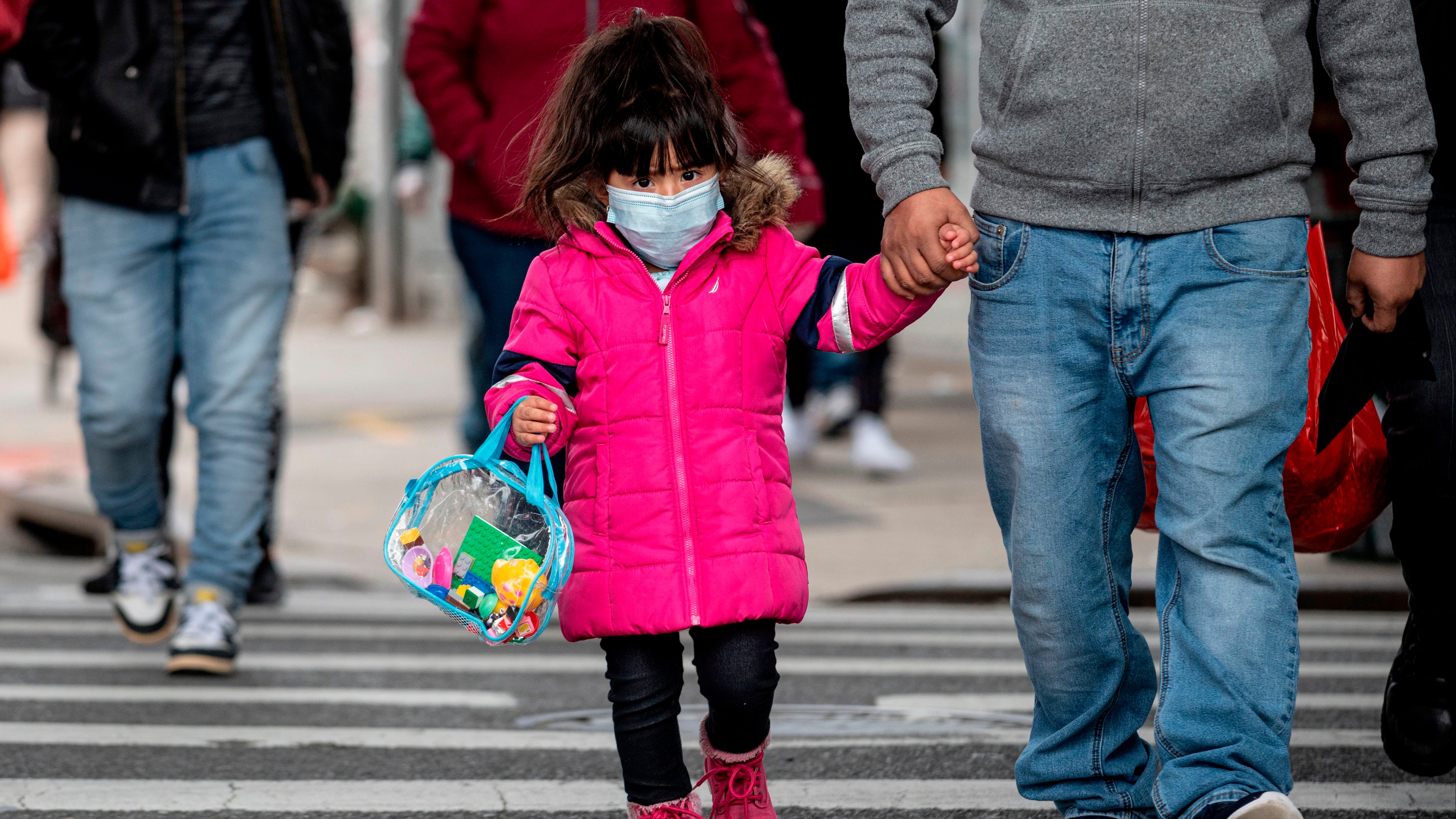 A girl, wearing a mask, walks down a street in the Corona neighborhood of Queens on April 14, 2020 in New York City.