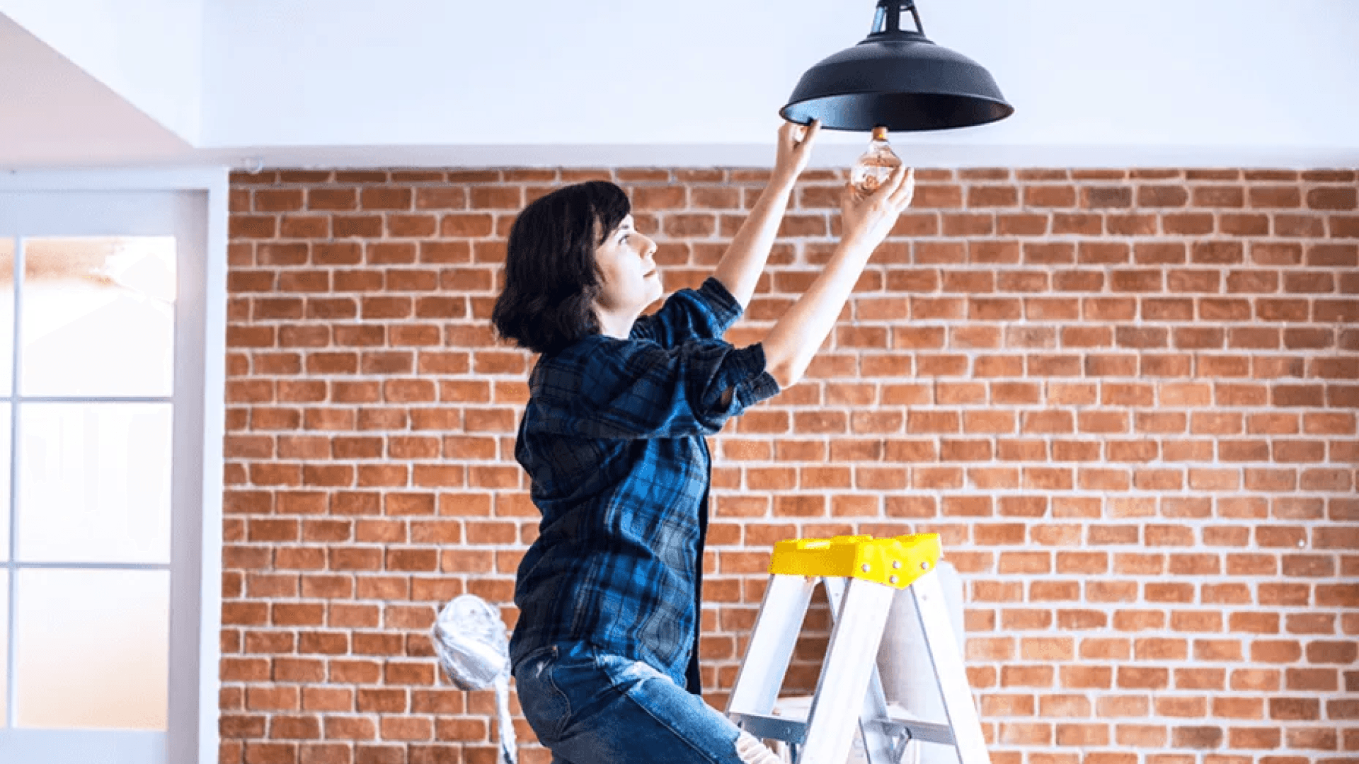 Woman on ladder installing lightbulb