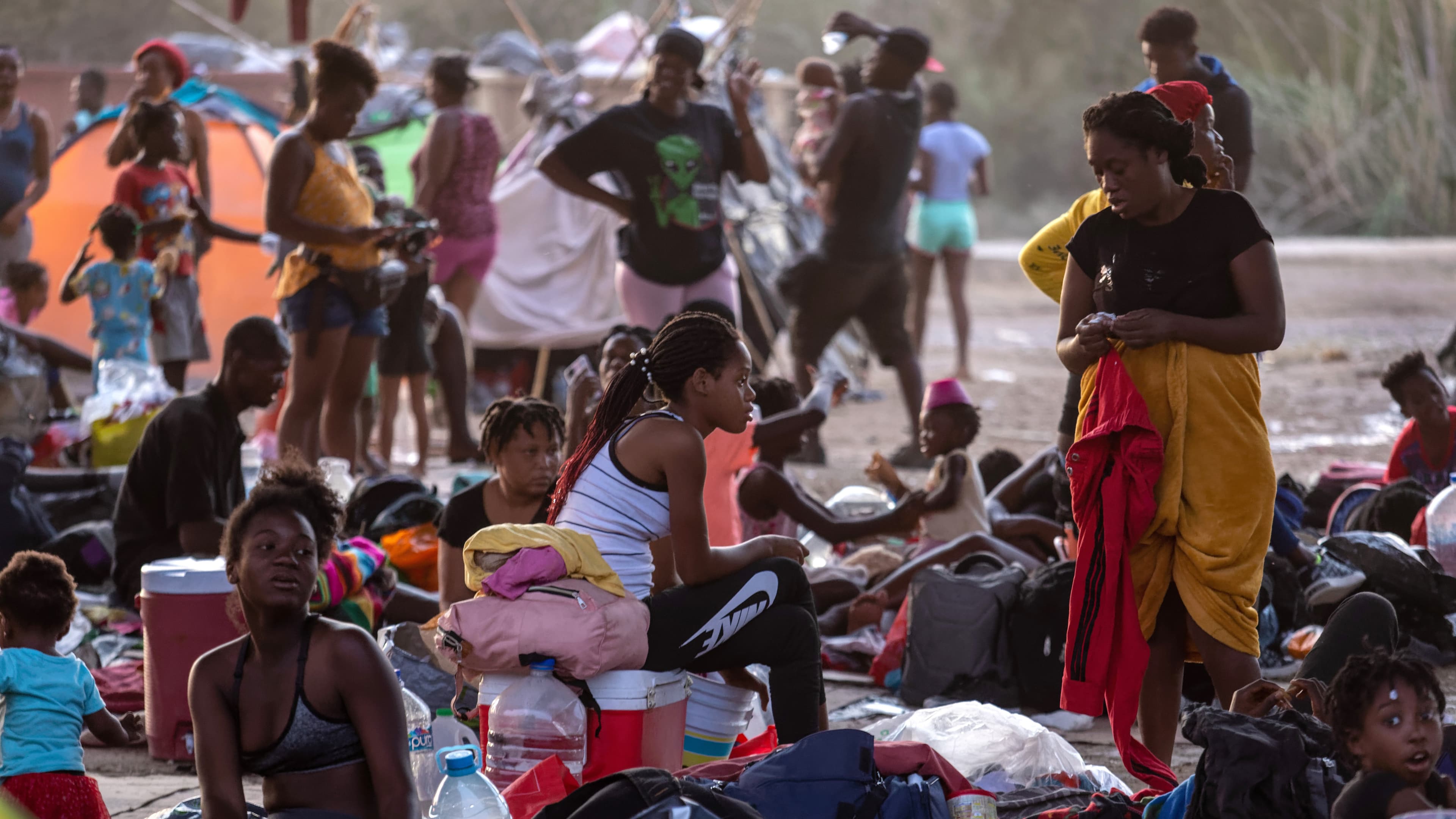 Immigrants sit and lie under the international bridge at a migrant camp on the U.S.-Mexico border on September 21, 2021 in Del Rio, Texas.