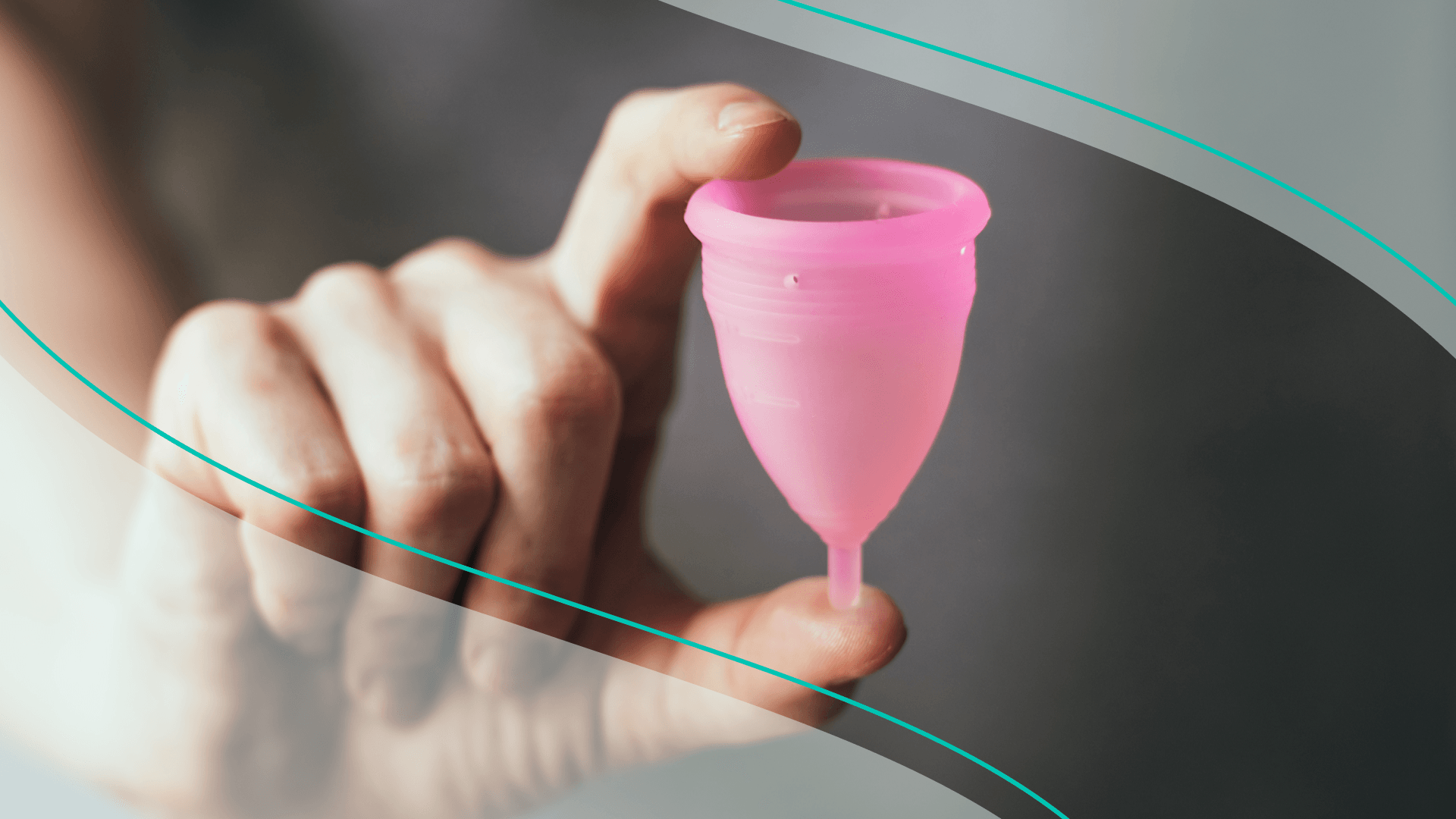 A person's hand holding a pink menstrual cup