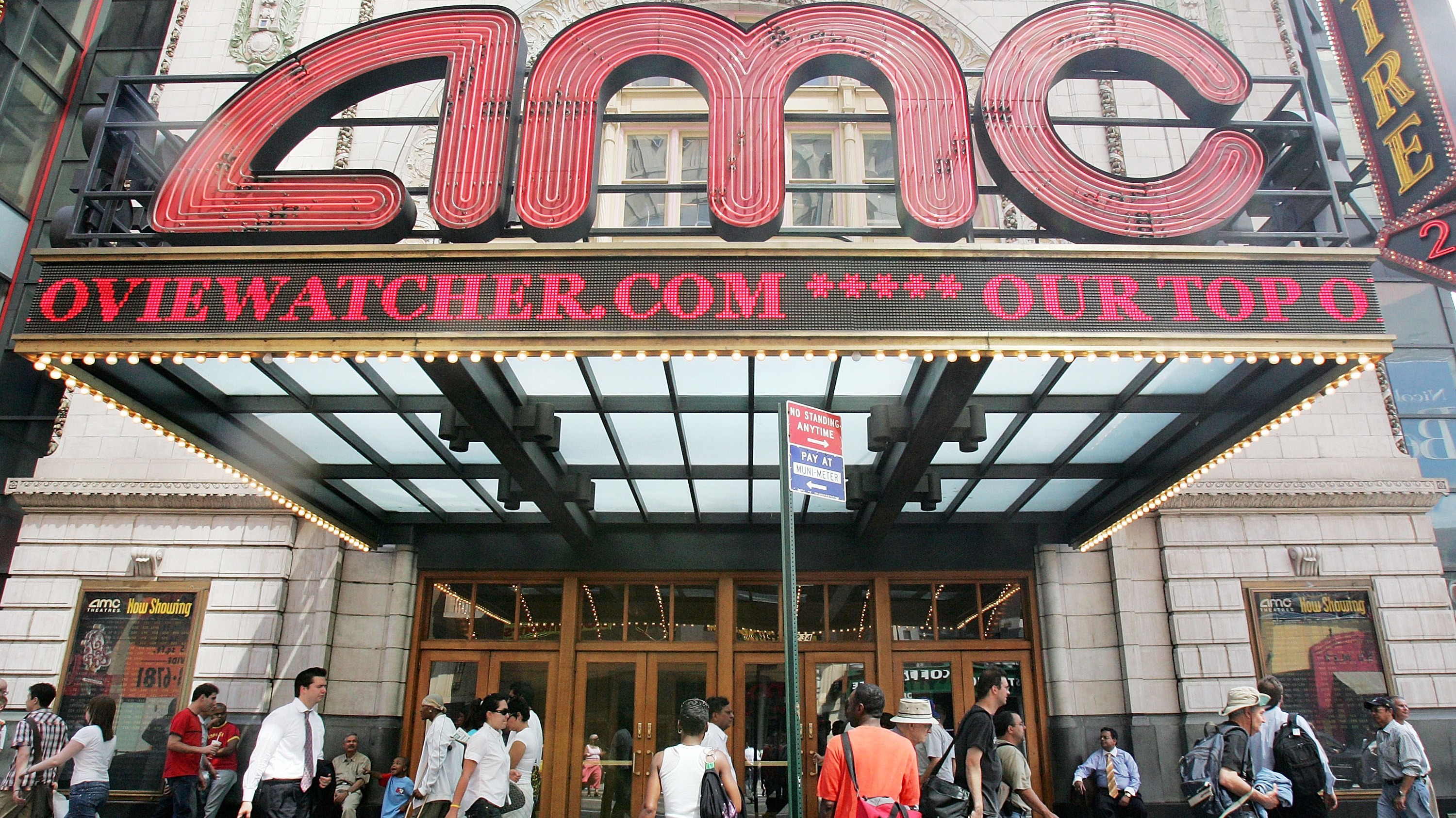 Pedestrians pass an AMC movie theater in Times Square June 21, 2005 in New York City.