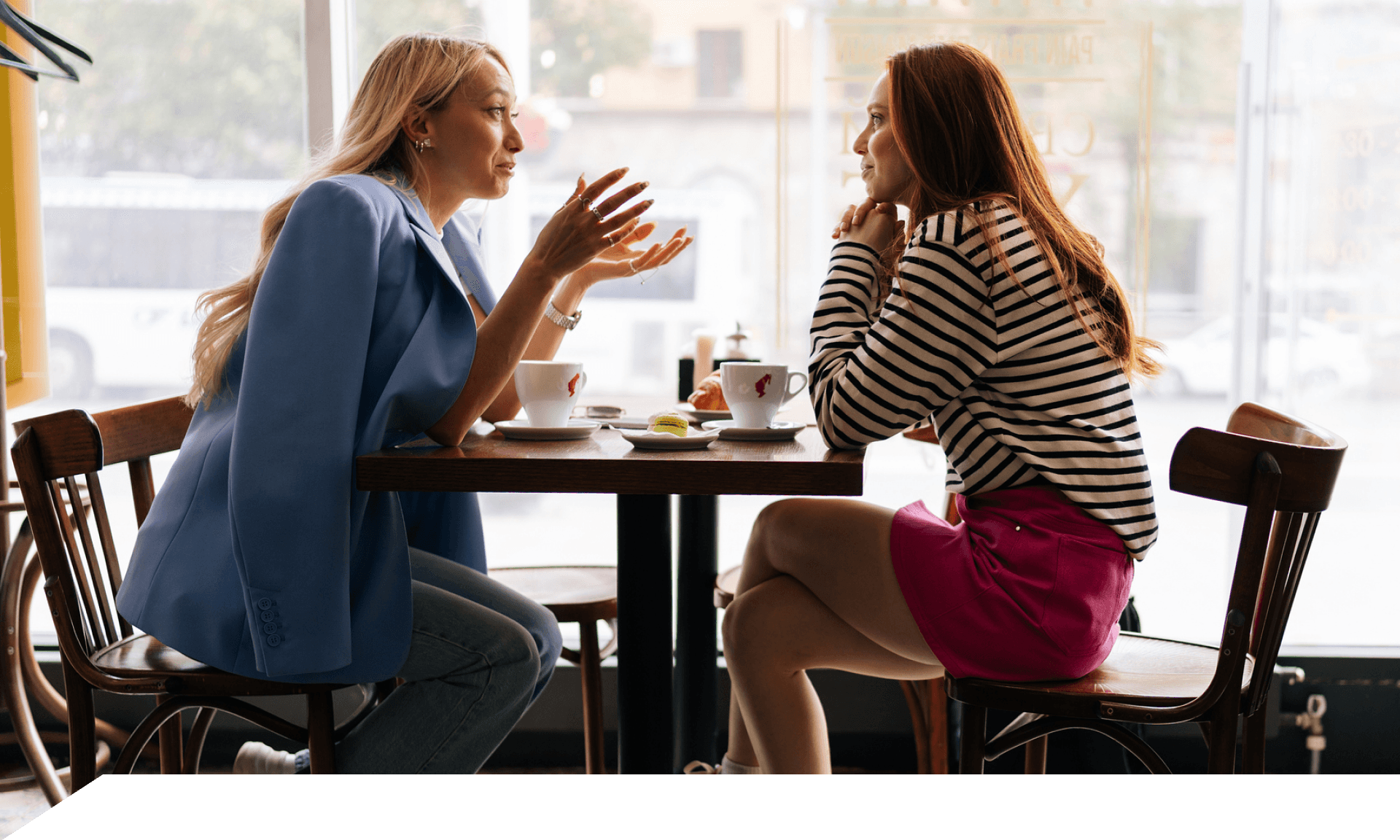 Two women talking, sitting at a coffee shop