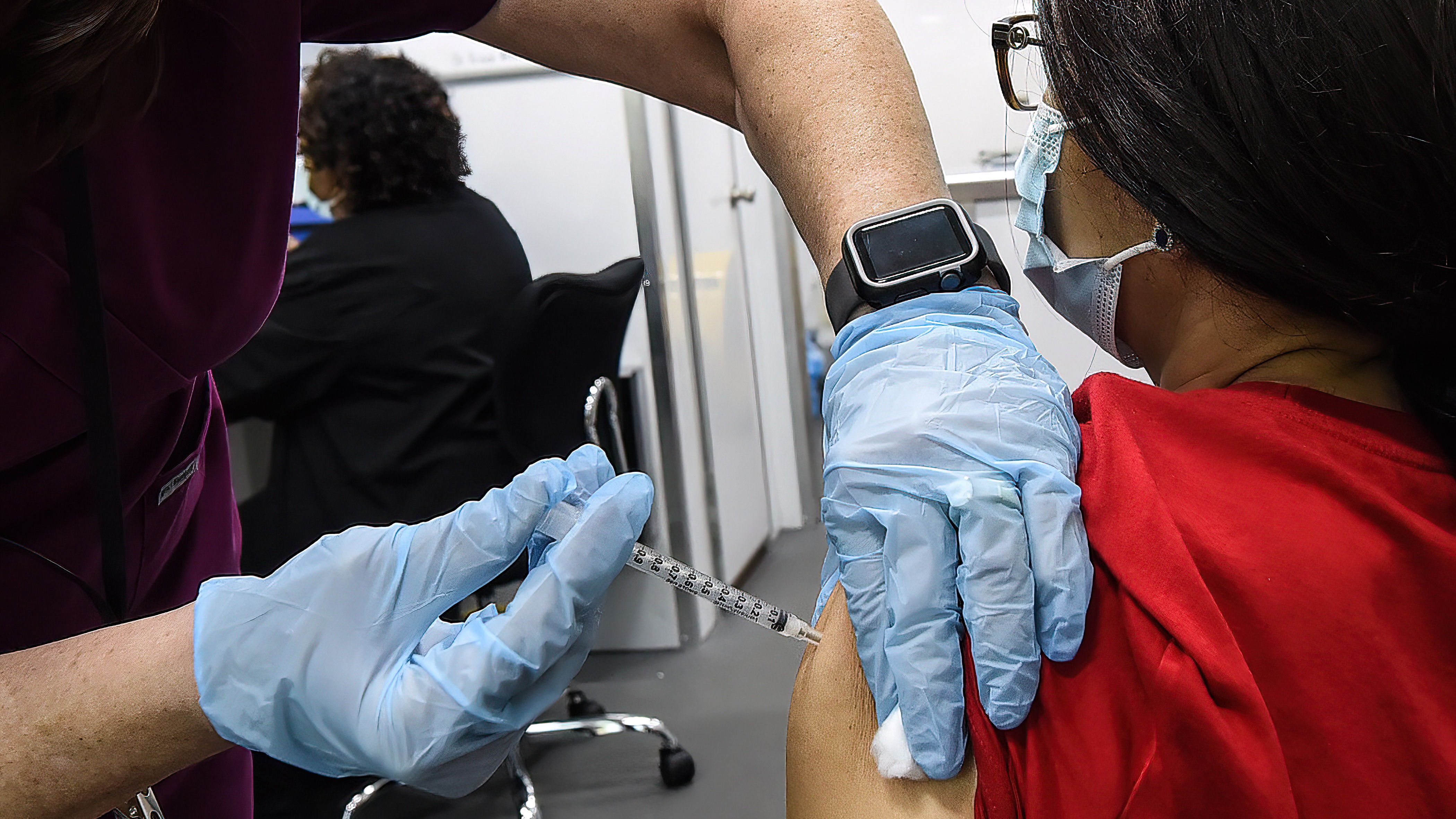 A nurse administers a dose of COVID-19 vaccine to a woman at a mobile vaccination event