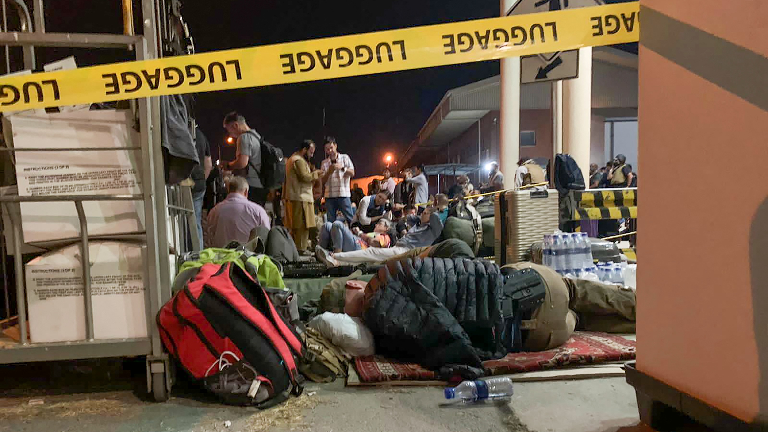 French and Afghan nationals wait to board a French military transport plane at the airport in Kabul