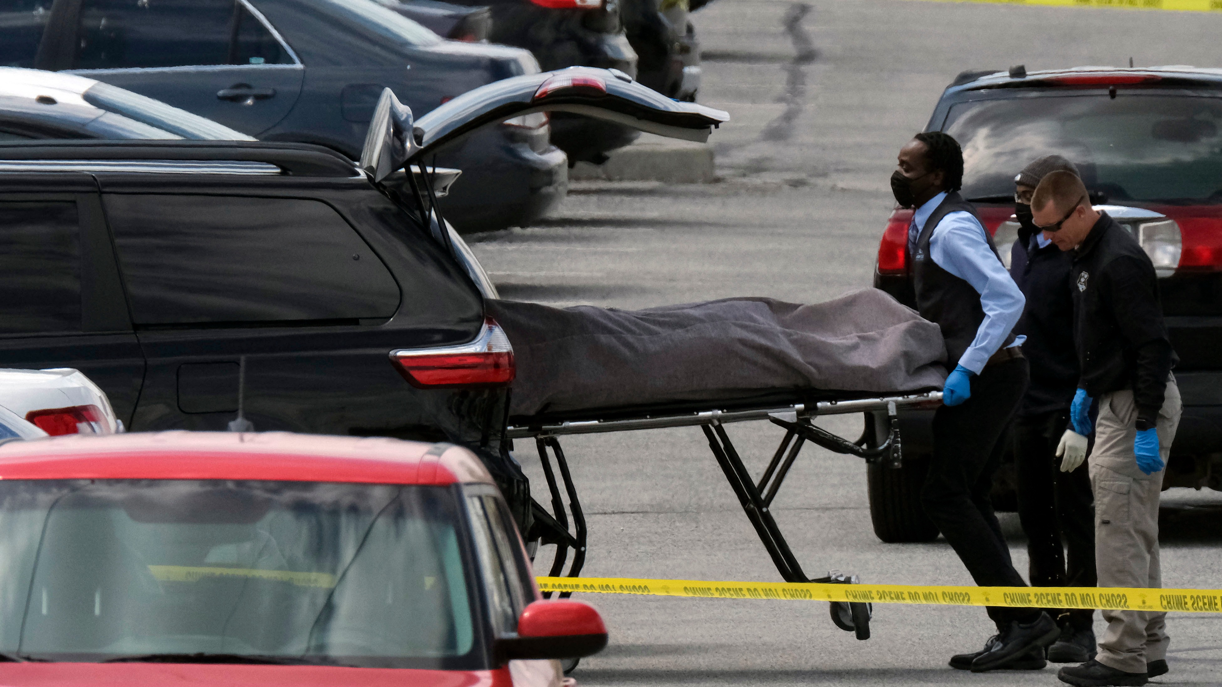 Officials load a body into a vehicle at the site of a mass shooting at a FedEx facility in Indianapolis, Indiana, on April 16, 2021.
